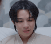 a young man with long black hair is laying in a hospital bed