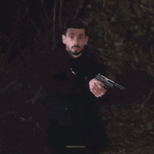 a man in a black coat is holding a gun in a blurry photo by minimalmoons