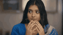 a woman in a blue shirt has her hands folded