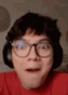 a close up of a man wearing glasses and headphones making a surprised face .