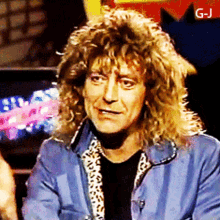 a man with long curly hair is wearing a blue jacket with a leopard print collar