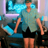 a man is standing in front of a neon sign that says legro