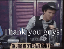 a man in a hat is sitting at a desk with a sign that says " thank you guys "