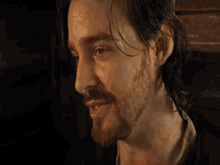 a close up of a man 's face with a beard and long hair