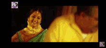 a woman in a green saree is smiling next to a man in a yellow shirt .