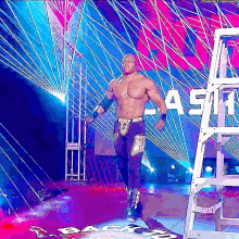 a wrestler is walking down a stage with a ladder in front of a sign that says ash