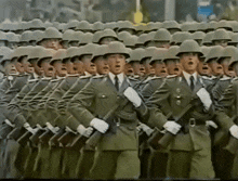 a row of soldiers marching in a parade wearing helmets and holding guns