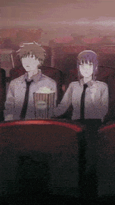 a man and a woman are sitting in a theater watching a movie and eating popcorn .
