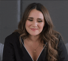 a woman wearing a black shirt and a gold necklace with the letter a on it