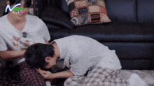 two men are sitting on the floor in front of a couch with the word now on the bottom