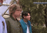 a man in a green jacket is standing next to another man