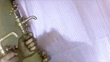 a person is holding a faucet in their hand in front of a curtain .