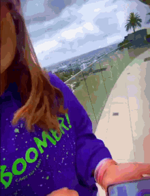 a girl wearing a purple boomer sweater takes a picture of herself