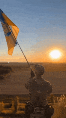 a man in a military uniform holds a flag in front of the sunset