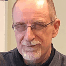 a man with a beard wearing glasses and a black shirt