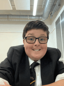 a young boy wearing glasses and a suit with the word pa on the tie