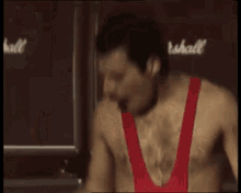 a man without a shirt is lifting a barbell in a gym .