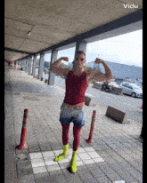 a man flexes his muscles in front of a sign that says ' vido '