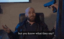a bald man with a beard is talking to someone holding a gun with the words but you know what they say below him