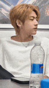 a young man sitting at a table with a bottle of aquafina water