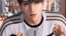 a young man wearing a striped shirt and a necklace is holding a cell phone .