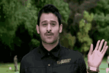 a man with a mustache is wearing a black shirt that says dsquared2