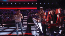 a man is dancing on a stage while a man sits in the audience watching the show