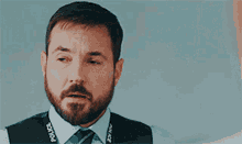 a man with a beard wearing a police vest and tie