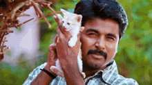 a man with a mustache is holding a white kitten