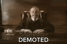 a judge is sitting at a desk with the word demoted on the table