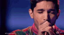 a man singing into a microphone with #songland on the bottom right