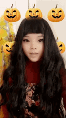 a woman wearing a wig has pumpkins on her head