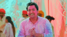 a man in a pink shirt is smiling and clapping his hands
