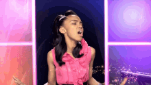 a girl in a pink ruffled top is singing with her eyes closed