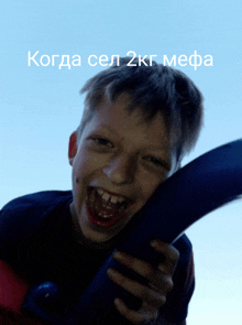 a young boy is smiling and holding a blue object in front of a blue sky with the words " когда сел 2кг мефа "