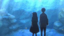 a man and a woman are standing in front of an aquarium