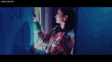a woman in a colorful sweater is standing in front of a locker door .