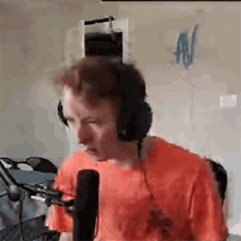 a man wearing headphones and a red shirt is talking into a microphone .