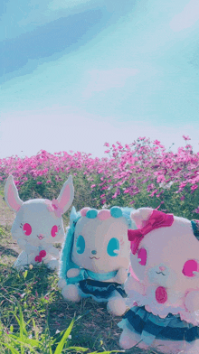 three stuffed animals in a field of pink flowers