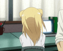 a girl with blonde hair is looking at a laptop