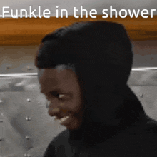 a man in a black hoodie is smiling with the words funkle in the shower above him