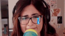 a woman wearing glasses and headphones is crying while holding a baby bottle