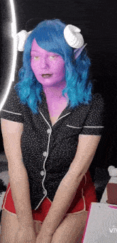a woman with blue hair and purple face paint is standing in front of a ring light