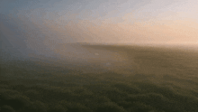 the sun is shining through the fog over a field