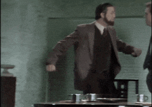 a man in a suit stands in front of a table