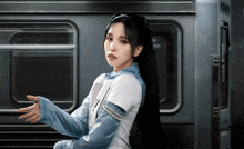 a woman with long black hair stands in front of a train