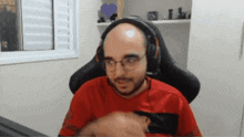 a bald man wearing glasses and headphones sits in a chair