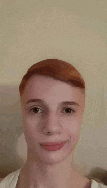 a young man with red hair is wearing a white tank top and smiling