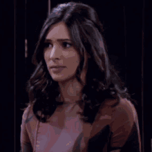 a woman with long dark hair is wearing a pink top and a black jacket .