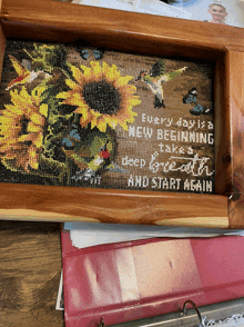 a cross stitched picture of sunflowers and hummingbirds says " every day is a new beginning "